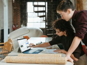 a man and a woman are looking at a laptop